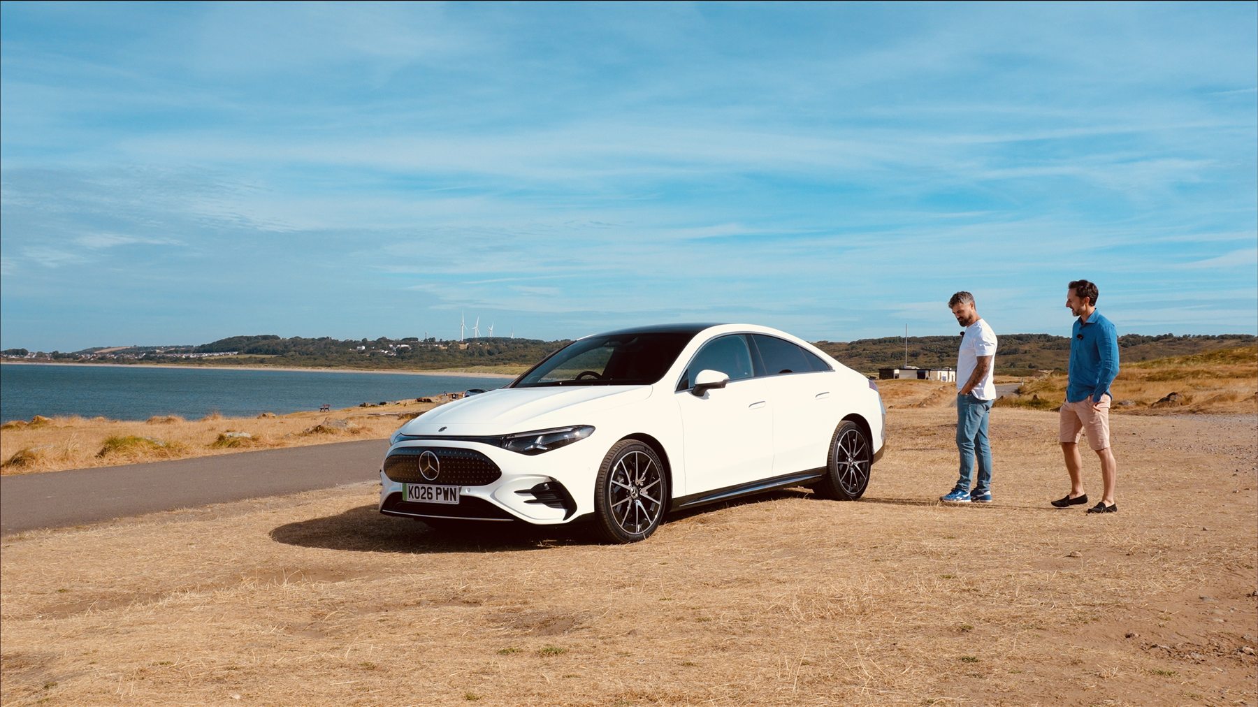 Josh Llewellyn-Jones discussing a Mercedes beside the coast
