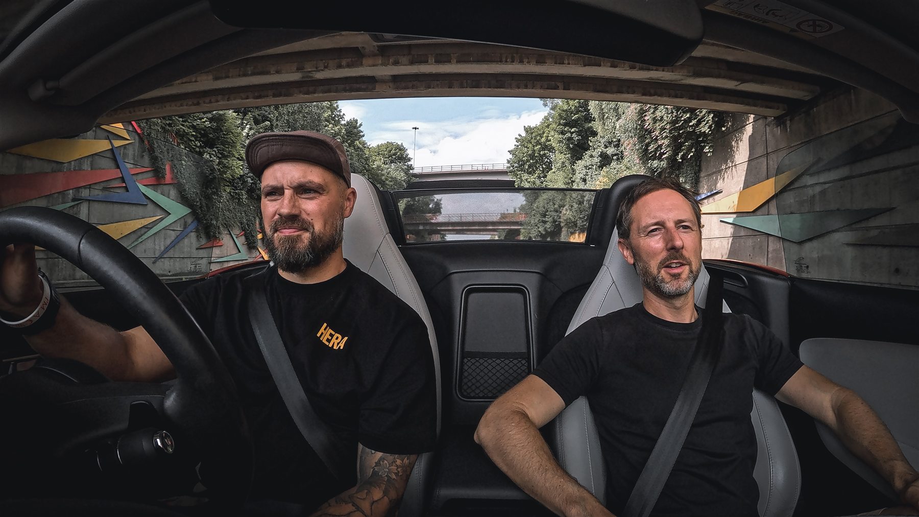 Josh driving a convertible with a passenger